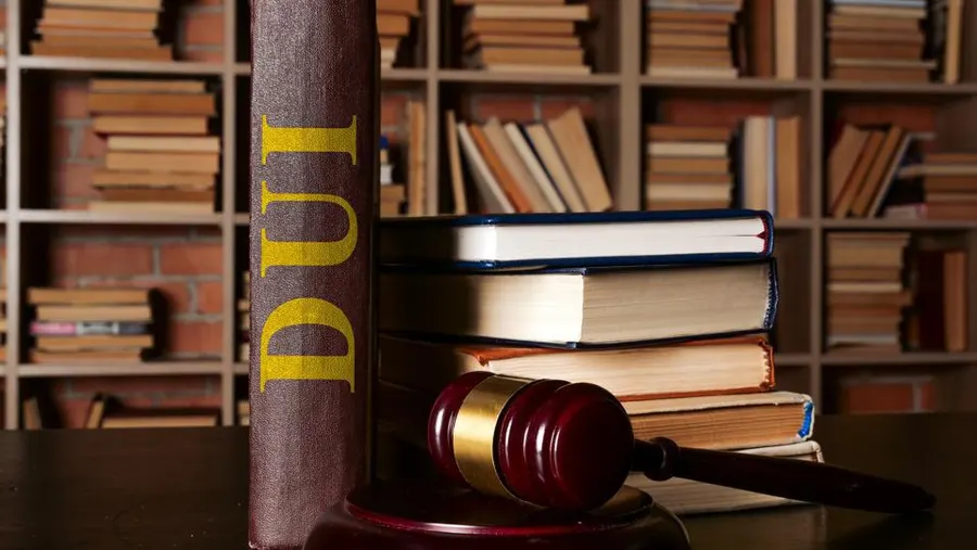 DUI legal book with yellow lettering and a gavel on a desk, surrounded by stacked law books, symbolizing DUI penalties and legal representation in Texas.