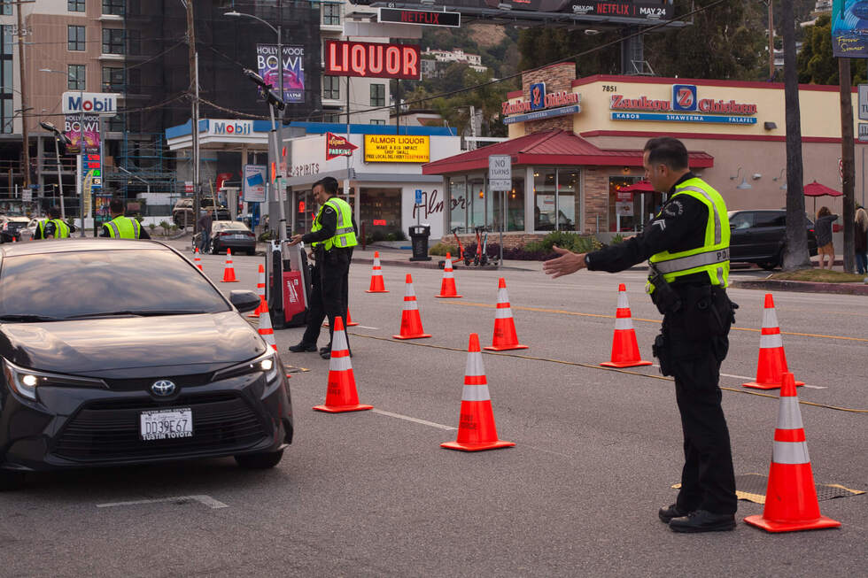 Police officers directing traffic at a DUI checkpoint with orange cones and a black Toyota vehicle approaching, highlighting law enforcement procedures related to DUI arrests.