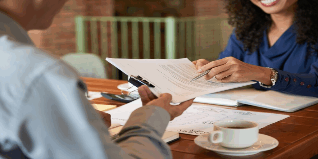 Two people discussing legal documents at a table, one pointing to the papers while the other holds them, with coffee cup and notepad visible, illustrating a consultation about DUI legal matters.