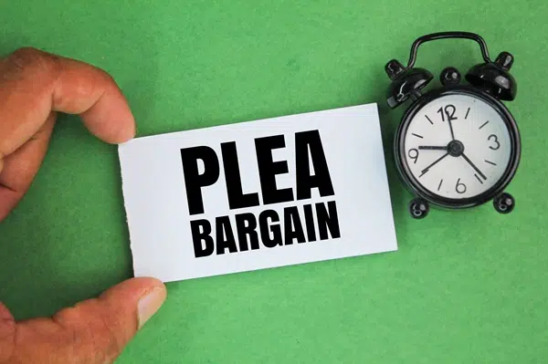 Hand holding a card with the text "PLEA BARGAIN" next to a clock, emphasizing legal options for DUI cases in Texas.