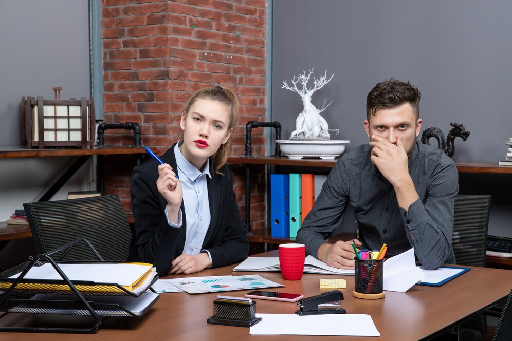 Management team in an office, discussing documents and strategies related to DWI cases, featuring a focused woman holding a pen and a thoughtful man, with charts and legal materials on the table.