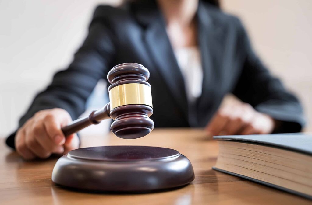 Lawyer in a suit holding a gavel, symbolizing legal authority and the judicial process, with a law book on the table, relevant to DWI defense and ALR hearings in Texas.