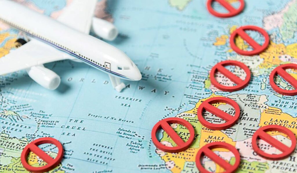 Airplane model on world map with red "no entry" signs indicating countries with DUI travel restrictions.