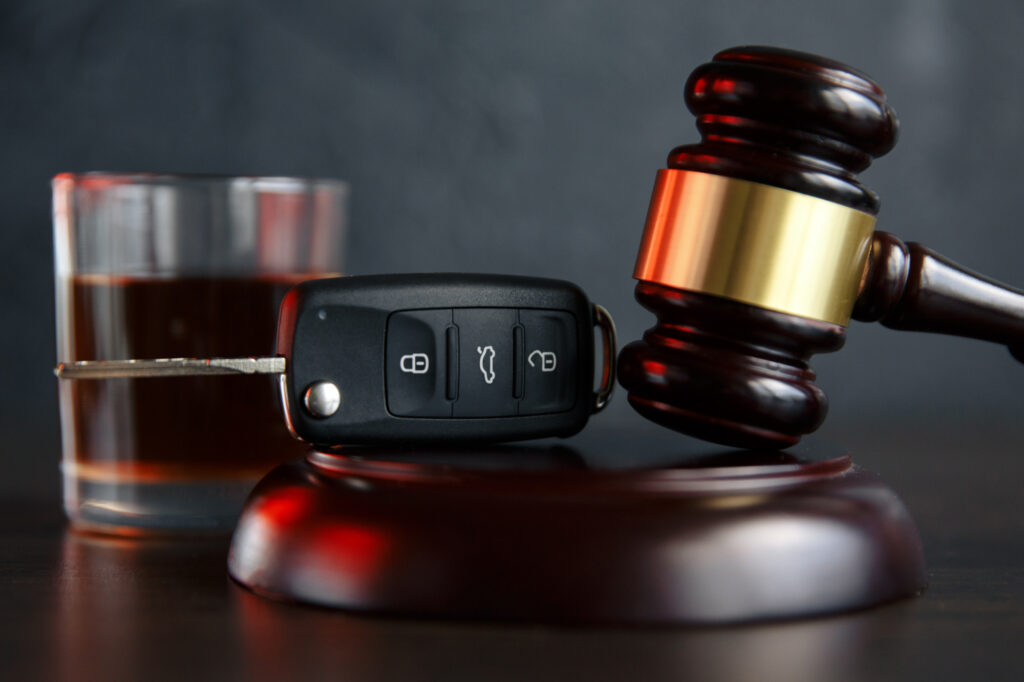 Gavel, car key, and glass of whiskey symbolizing DUI legal issues and consequences in Texas.