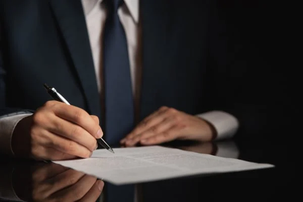 Person in a suit signing legal documents, reflecting the legal processes involved in DUI defense in Texas.