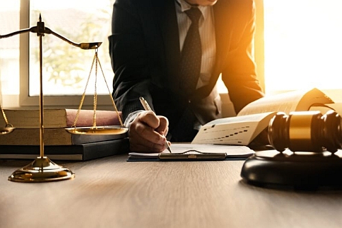Lawyer writing notes at a desk with legal books, a gavel, and a scale of justice, representing DUI legal services and consultation in Texas.