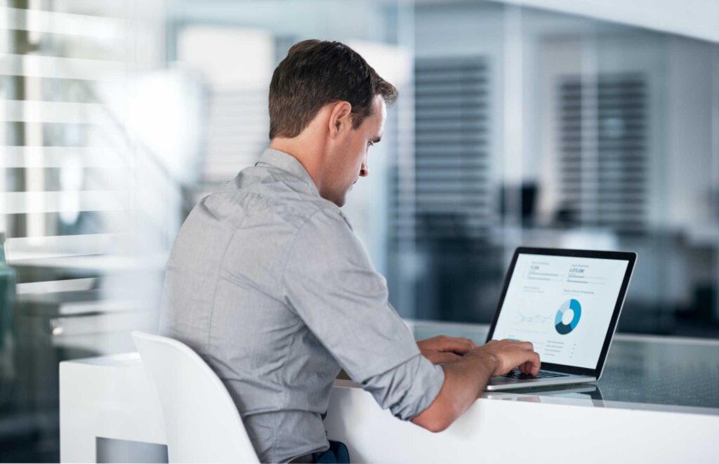 Man working on a laptop displaying data analysis, relevant to legal considerations for real estate agents with a DWI record.