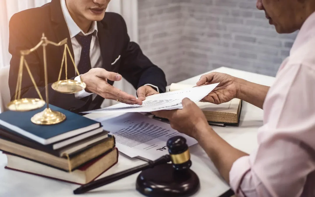 Lawyer discussing legal documents with a client, scales of justice and gavel on the table, representing criminal defense services.